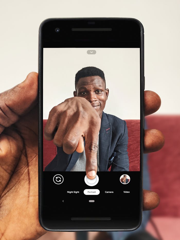 services-02 Portrait of a man using a smartphone to take a selfie indoors.